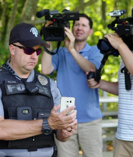 A first responder shows their aerial cell phone connectivity to members of the media.